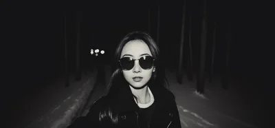 Young Woman Wearing Sunglasses Walking Through Snowy Forest