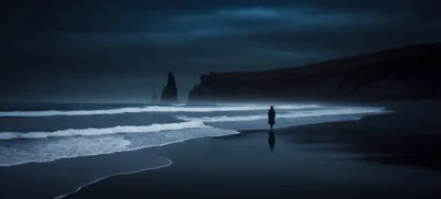 Lone Person Walking Along Dark Icelandic Beach