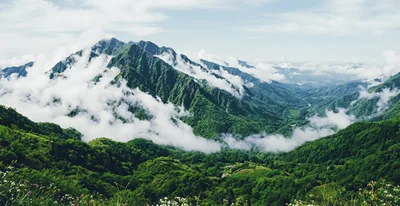 Lush Green Mountain Range With Rolling Clouds