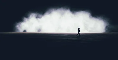 Silhouette Of A Person Walking Toward A Glowing Cloud