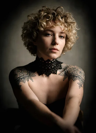 Portrait Of A Woman With Curly Blonde Hair And Tattoos