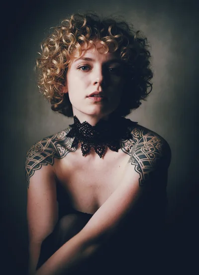 Portrait Of A Young Woman With Curly Hair And Tattoos