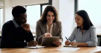 Diverse Business Team Collaborating On Tablet In Office