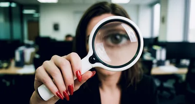 Businesswoman Looking Through Magnifying Glass In Office