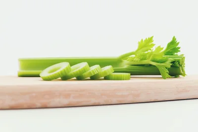Fresh Celery Stalks Sliced on a Wooden Cutting Board