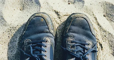 Pair Of Blue Sneakers Standing On Sandy Beach