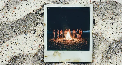 Group Of Friends Gathering Around A Beach Bonfire