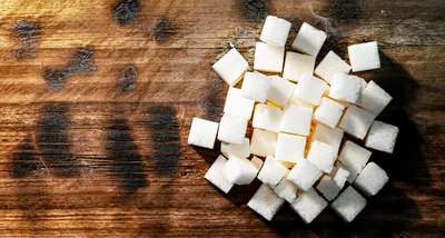 White Sugar Cubes Scattered On A Wooden Table