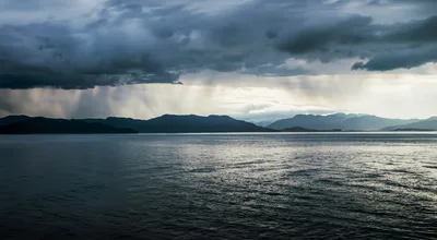 Rain Showers Over Distant Mountains And Calm Ocean