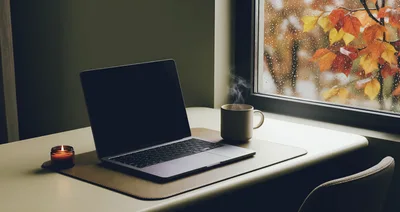 Laptop And Steaming Coffee On Desk By Rainy Window