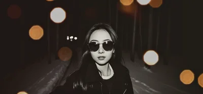 Young Woman Wearing Sunglasses In A Snowy Forest At Night