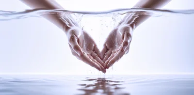 Cupped Hands Emerging From Clear Water Surface