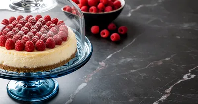 Cheesecake Topped With Fresh Raspberries Under Glass Dome
