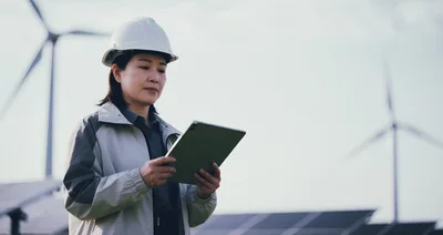 Female Engineer Inspecting Solar Farm With Tablet
