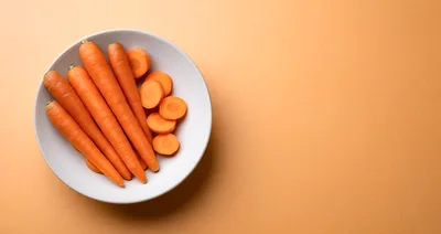 Fresh Whole And Sliced Carrots In A White Bowl