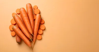 Fresh Whole And Sliced Carrots On Orange Background