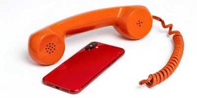 Vintage Orange Telephone Handset Beside Modern Red Smartphone