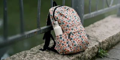 Floral Print Backpack With Water Bottle On Stone Wall