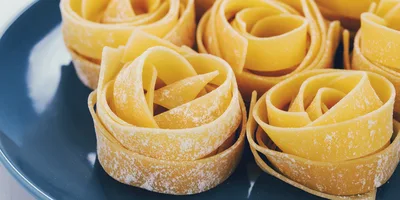 Raw Pappardelle Pasta Nests On A Blue Plate