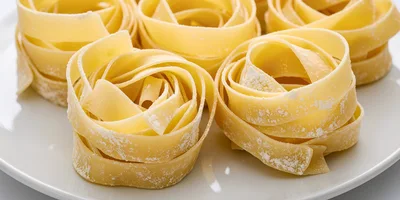 Raw Tagliatelle Pasta Nests on a White Plate