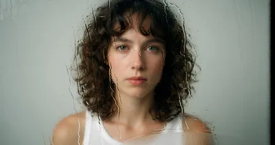 Young Woman Looking Through Rain Streaked Glass