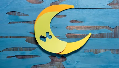 Paper Cutout Crescent Moon on Blue Wooden Background