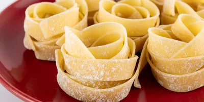 Raw Tagliatelle Pasta Nests On A Red Plate