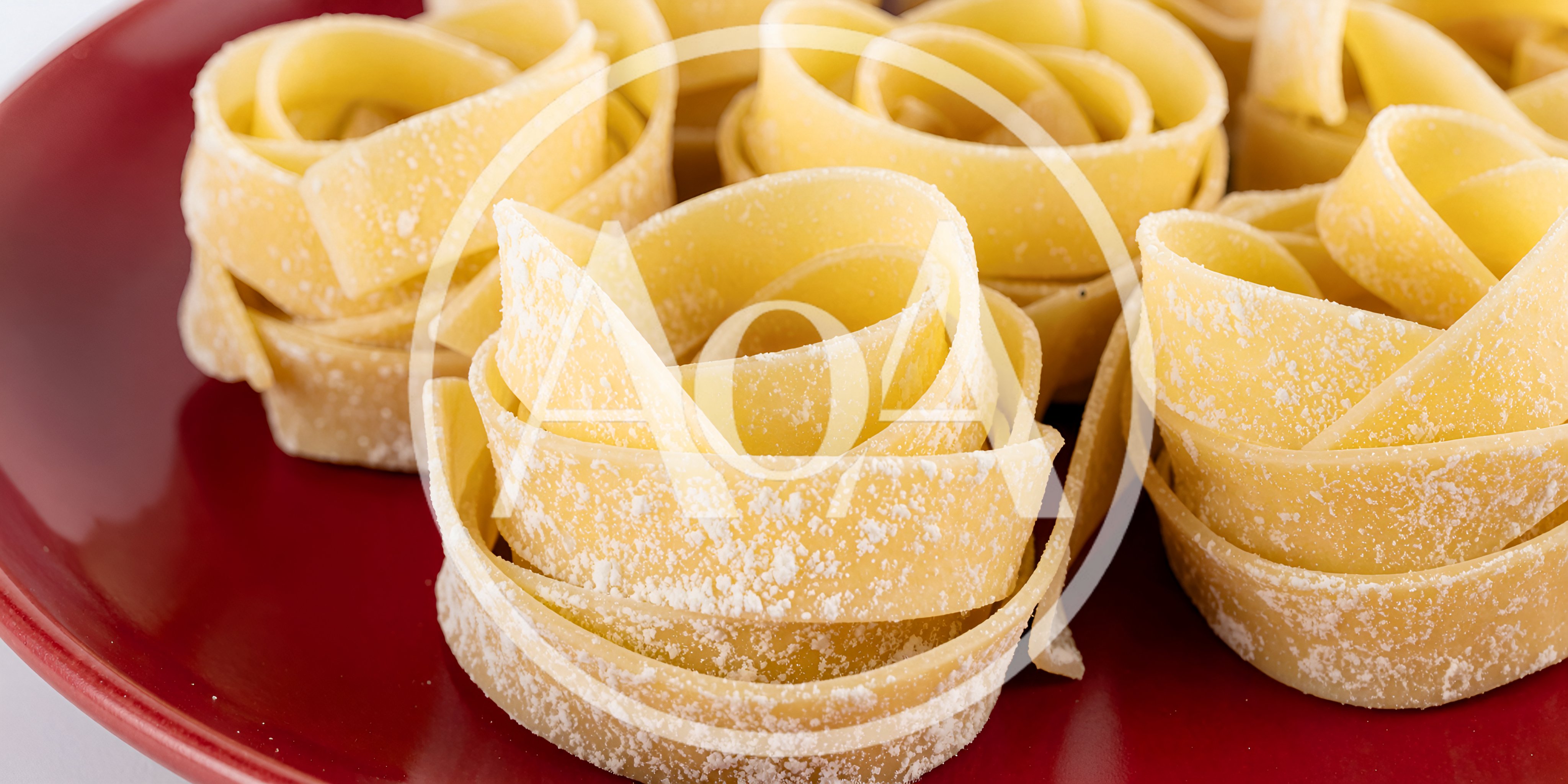 Raw Tagliatelle Pasta Nests On A Red Plate