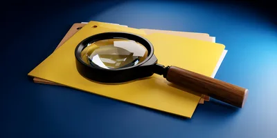 Magnifying Glass Resting On Yellow File Folders