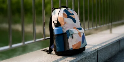 Patterned Backpack With Water Bottle On Concrete Ledge