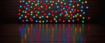 Colorful Christmas String Lights Against Dark Wooden Wall