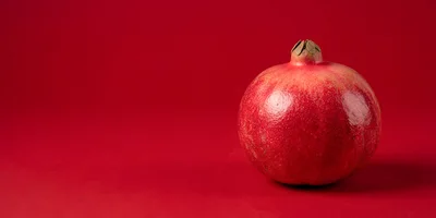 Single Fresh Pomegranate Fruit on Red Background