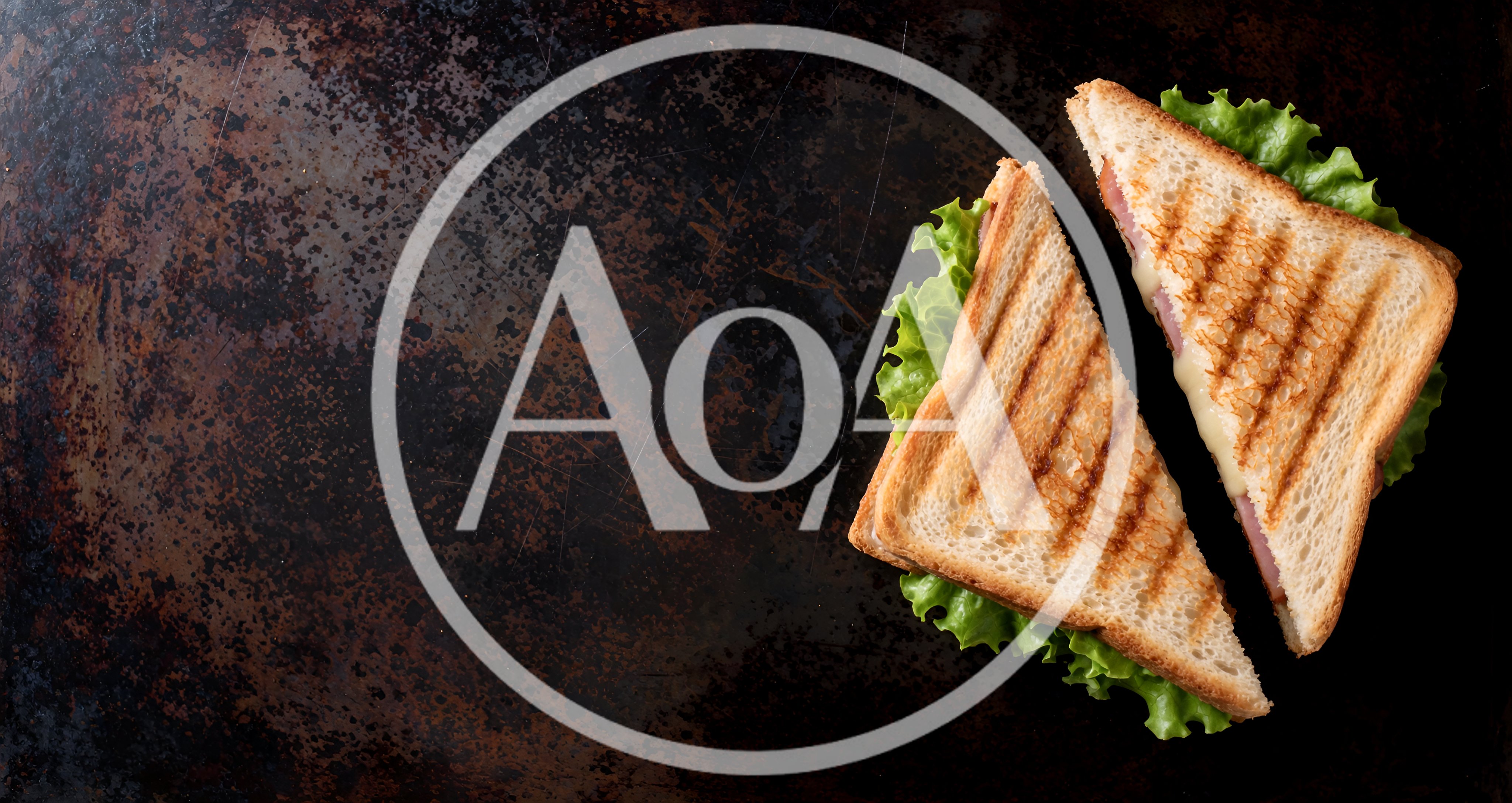 Two Grilled Ham and Cheese Sandwiches on Dark Surface