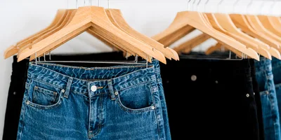 Blue And Black Denim Jeans On Wooden Hangers