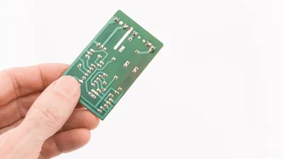 Hand Holding A Small Green Printed Circuit Board