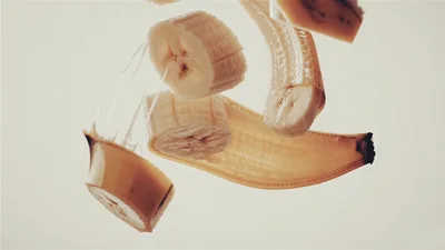Sliced Banana Pieces Falling Downwards Against White Background