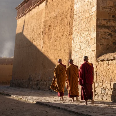 Three Buddhist Monks Walking Along Ancient Monastery Wall