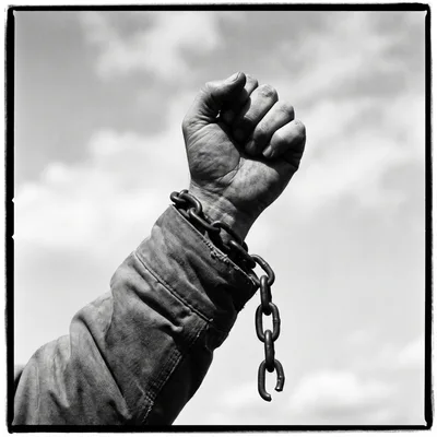 Raised Fist With Broken Chain Against Sky