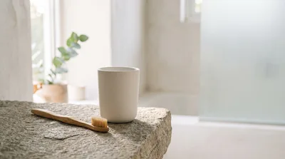 Bamboo Toothbrush And Ceramic Cup On Stone Countertop
