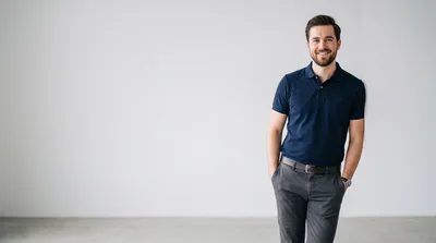Smiling Man Standing Against A Plain White Wall