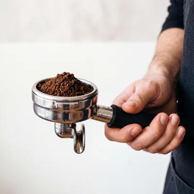 Barista Holding A Portafilter Filled With Ground Coffee