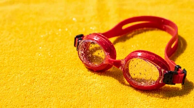 Red Swimming Goggles On A Yellow Towel