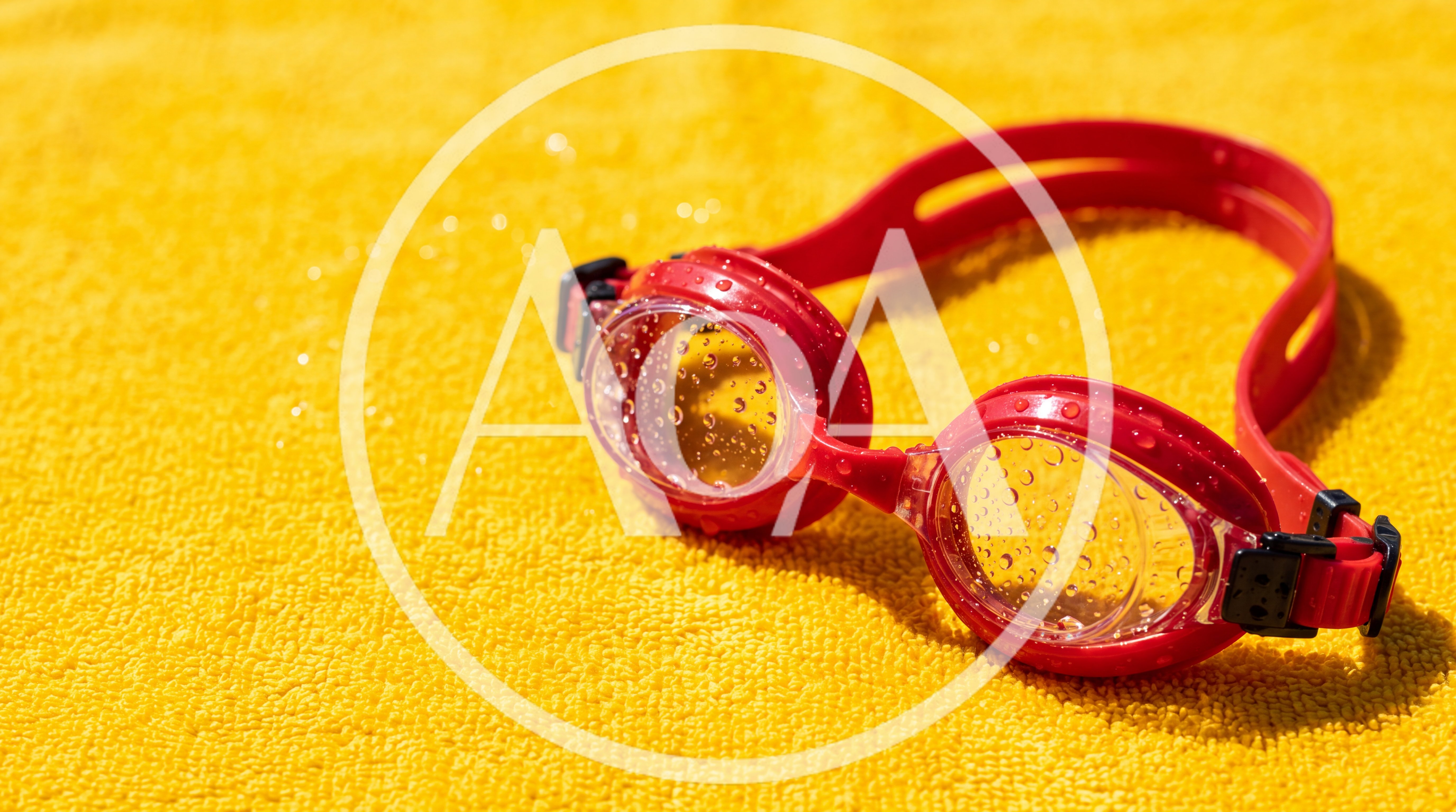 Red Swimming Goggles On A Yellow Towel