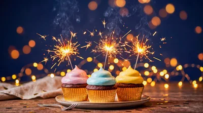 Three Cupcakes With Lit Sparklers On A Plate