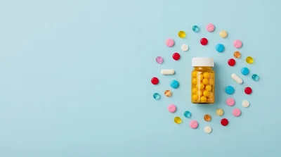 Pill Bottle Surrounded By Colorful Tablets On Blue Background