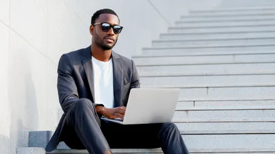 Young Black Businessman Working On Laptop On Outdoor Stairs