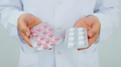 Doctor Holding Blister Packs of Pink and White Pills