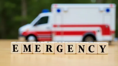 Wooden Blocks Spelling Emergency With Ambulance In Background