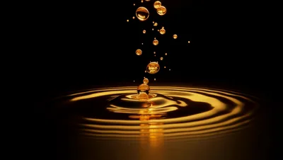 Golden Liquid Droplets Creating Ripples In Dark Background