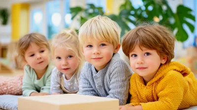 Four Young Children Lying Together On A Classroom Floor